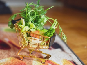 Modell-Einkaufswagen mit winzigem Gemüse befüllt.
